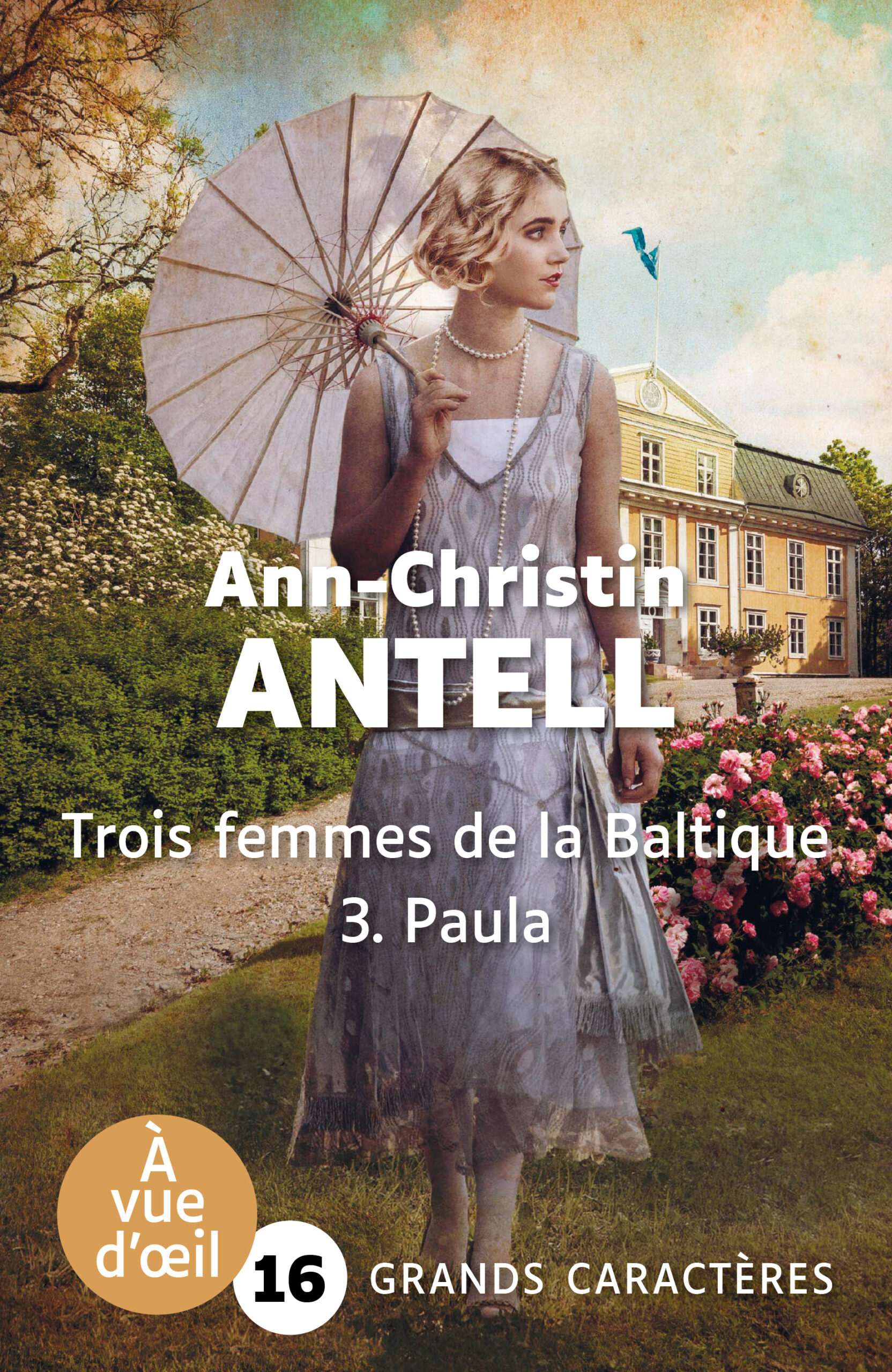 Femme en robe claire tenant une ombrelle devant une grande demeure entourée de fleurs, illustrant le livre en grands caractères Trois femmes de la Baltique 3. Paula d’Ann-Christin Antell
