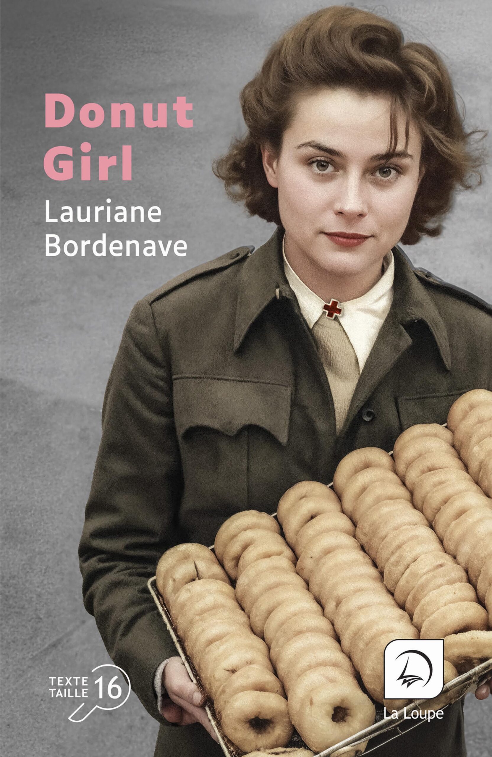 Couverture du livre en grands caractères intitulé Donut Girl de Lauriane Bordenave, publié par Les éditions de La Loupe. La photographie montre une jeune femme en tenue de travail, regardant face à l’objectif, tenant un plateau rempli de donuts alignés. Elle porte un uniforme sombre avec un col clair orné d’une petite croix rouge. L’arrière-plan est neutre, dans des tons gris, mettant en valeur le visage et les pâtisseries. Le titre apparaît en lettres roses et blanches dans la partie supérieure gauche. En bas de la couverture figure la mention « Texte taille 16 ».