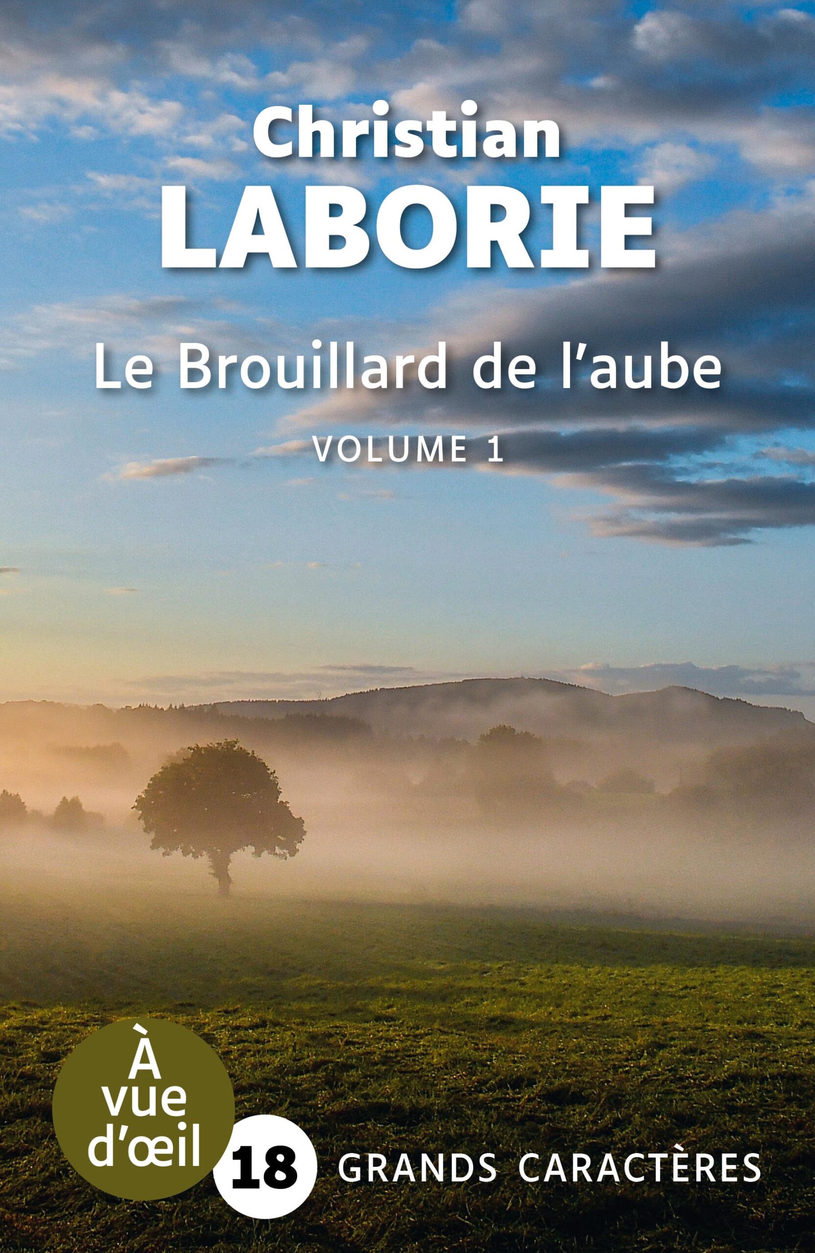 Couverture du livre en grands caractères intitulé Le Brouillard de l’aube – Volume 1 de Christian Laborie, publié par Les éditions À Vue d’œil. La couverture présente un paysage naturel au lever du jour : un arbre solitaire se dresse dans un champ recouvert de brume, avec des collines en arrière-plan et un ciel partiellement nuageux aux teintes bleutées et dorées. L’atmosphère est calme et lumineuse, évoquant le matin. Le nom de l’auteur apparaît en haut en grandes lettres blanches, et le titre au centre. En bas de la couverture figure la mention « Grands caractères » avec un corps 18.