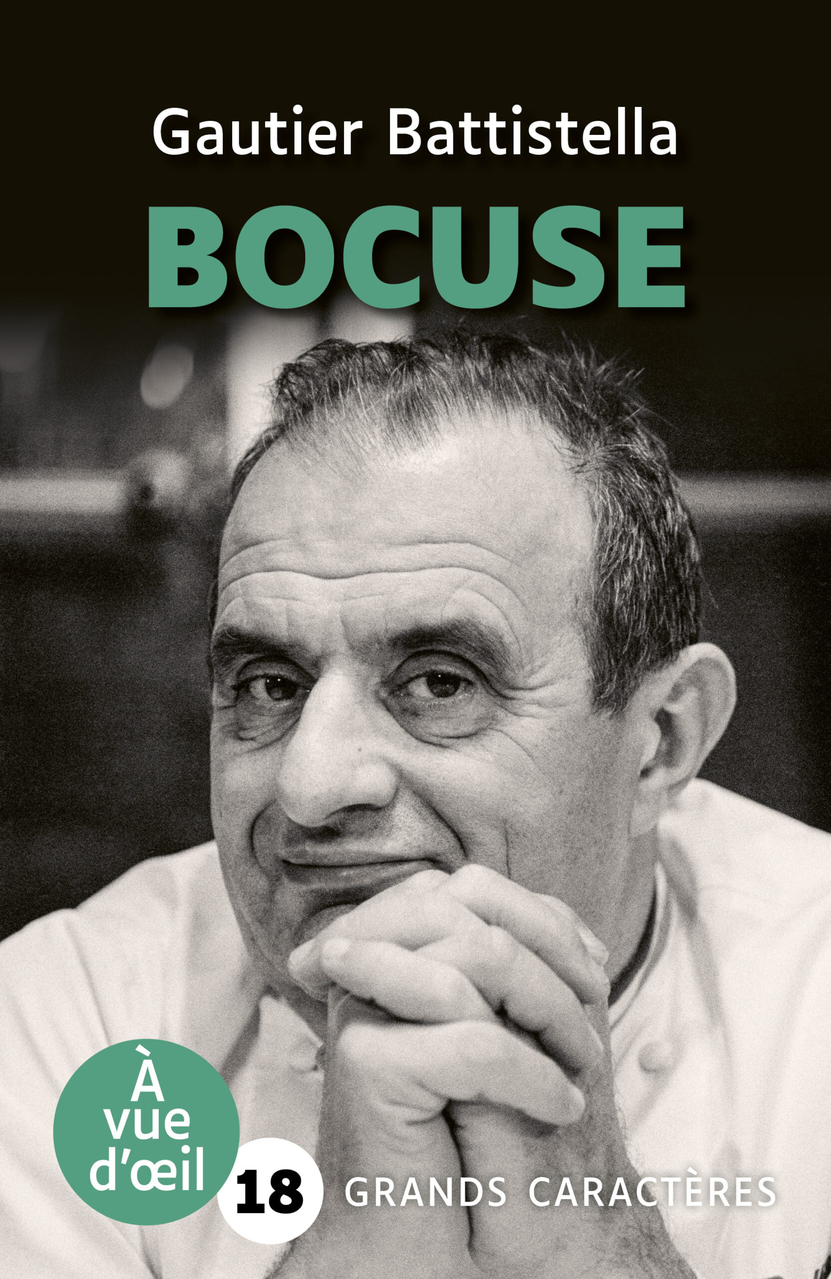Portrait en noir et blanc du chef Paul Bocuse, les mains jointes sous le menton, regard tourné vers l’objectif.